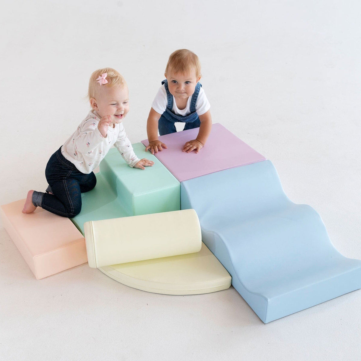 1. Two children playing on pastel foam blocks in a studio