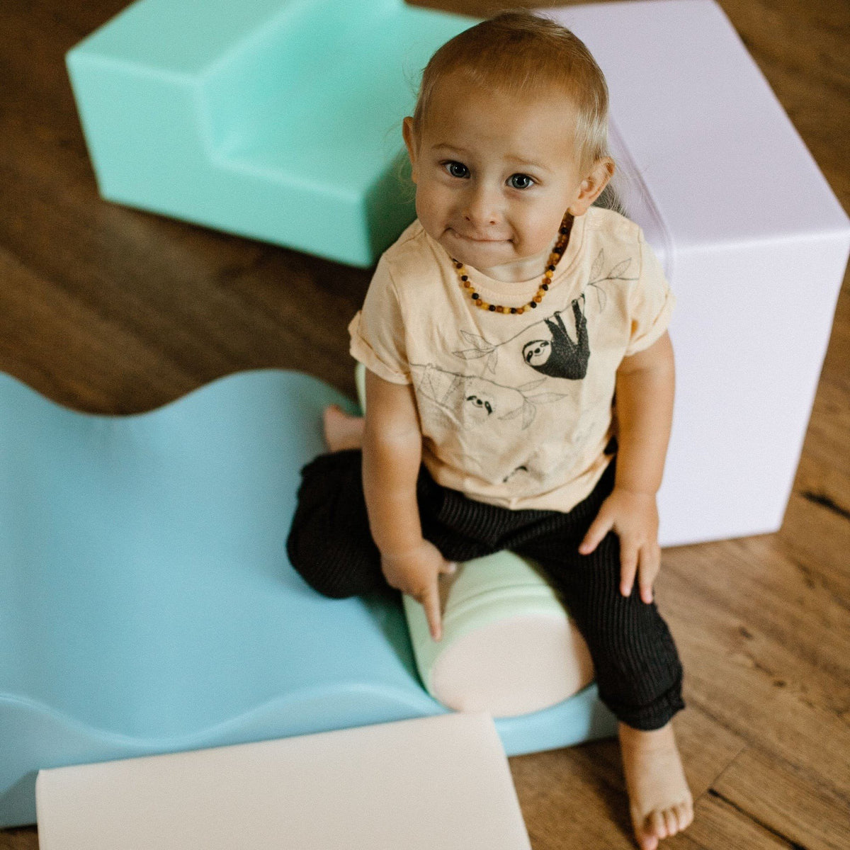 1. Toddler sitting on pastel foam blocks in a playroom setting