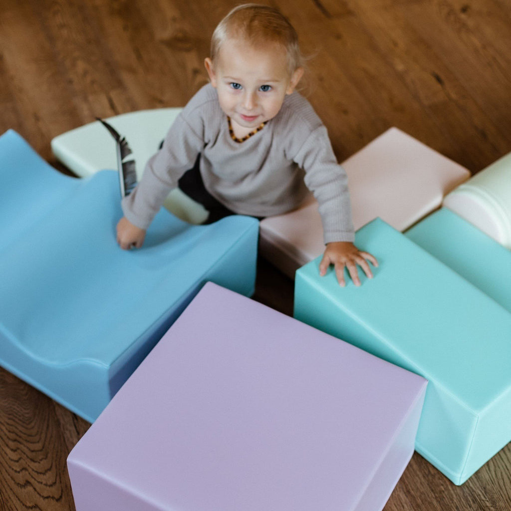 1. Child playing with pastel foam blocks on a wooden floor