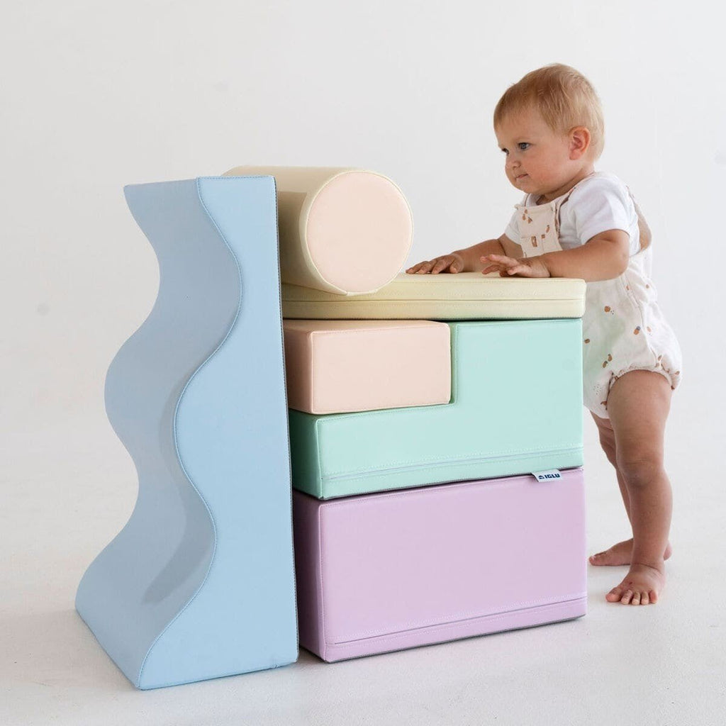 1. Toddler standing next to stacked pastel foam blocks