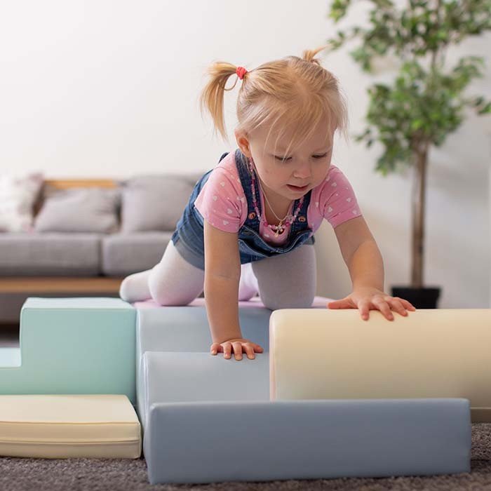 1. Child climbing on pastel foam blocks in a living room
