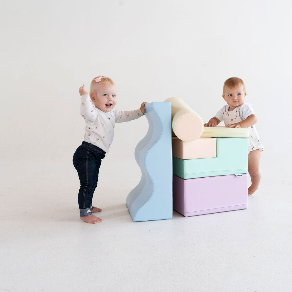 1. Two toddlers playing with stacked pastel foam blocks in a studio