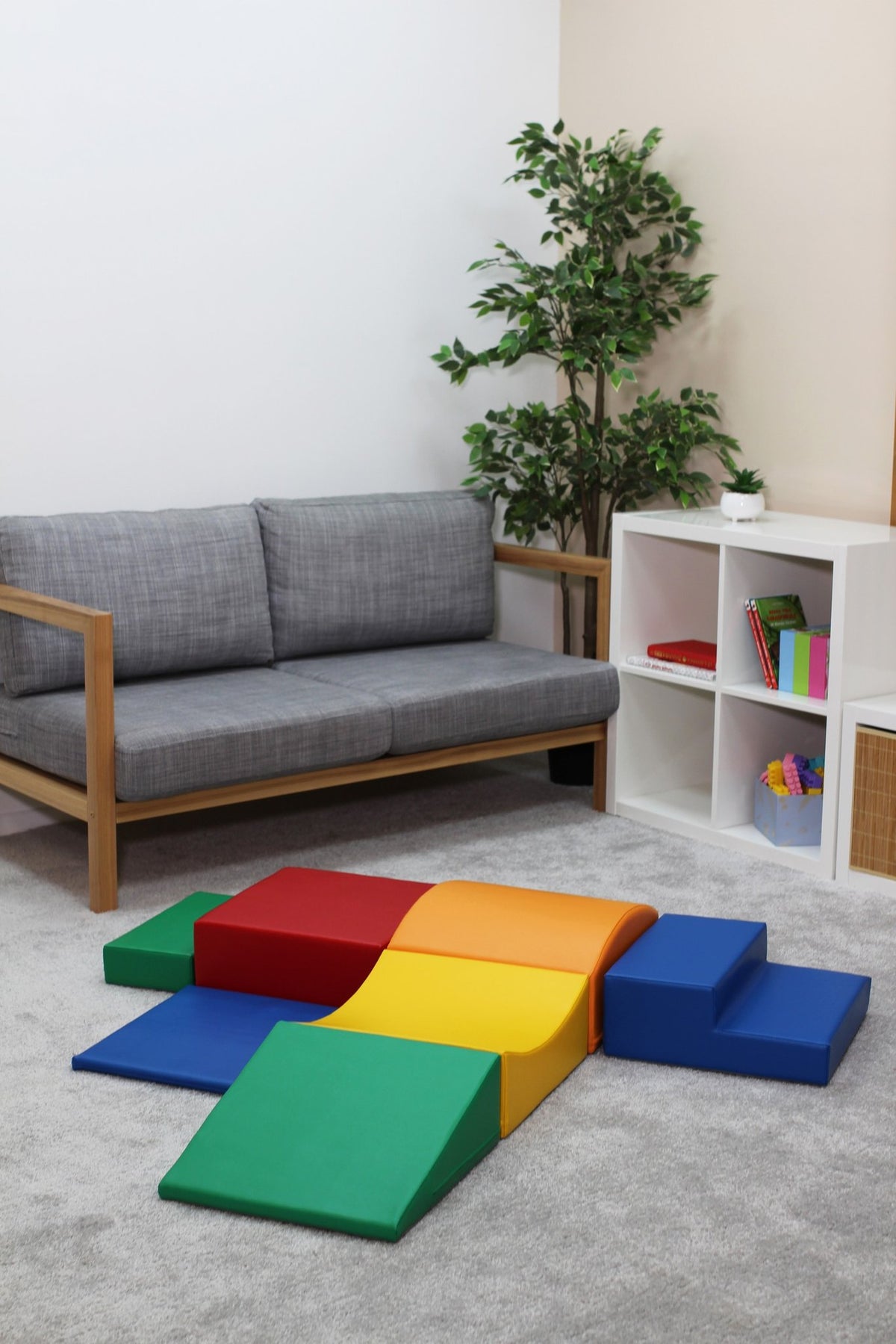 1. IGLU Little Crawler multicolor foam blocks arranged in a cross shape in a living room setting with grey sofa and white shelves