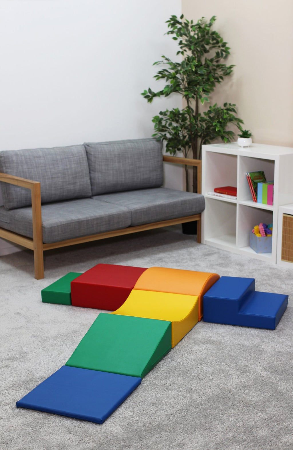 1. IGLU Little Crawler multicolor foam blocks arranged in a T-shape in a living room setting with grey sofa and white shelves