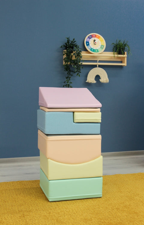 1. Stacked IGLU Little Crawler foam blocks in pastel colors against a blue wall with decorative shelf