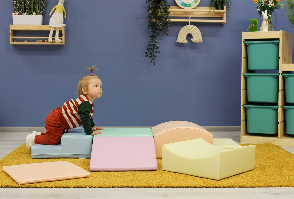 1. Child crawling on IGLU Little Crawler foam blocks in pastel colors in a playroom setting