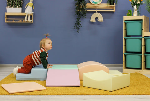 1. Child crawling on IGLU Little Crawler foam blocks in pastel colors in a playroom setting