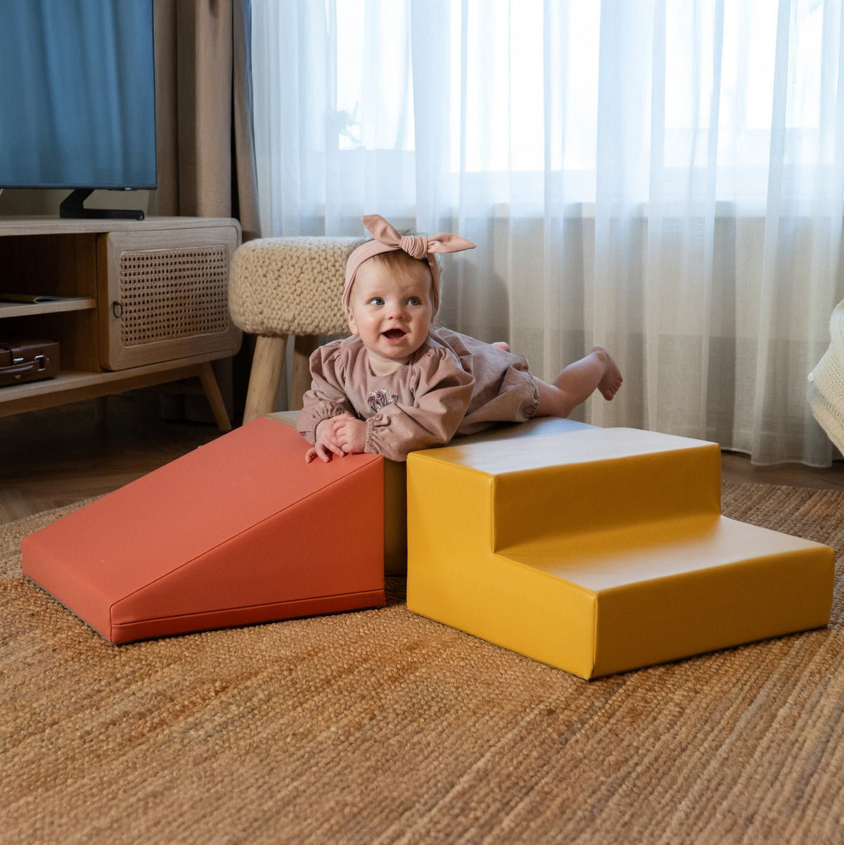 1. Baby girl in pink dress with headband lying on IGLU pastel pink and yellow foam blocks in a living room