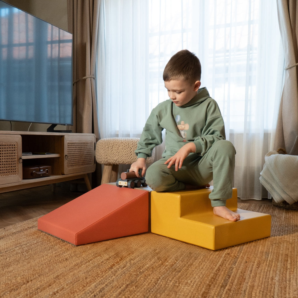 1. Young boy in green outfit playing on IGLU pastel pink and yellow foam blocks in a living room