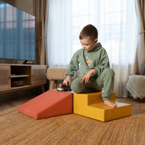 1. Young boy in green outfit playing on IGLU pastel pink and yellow foam blocks in a living room