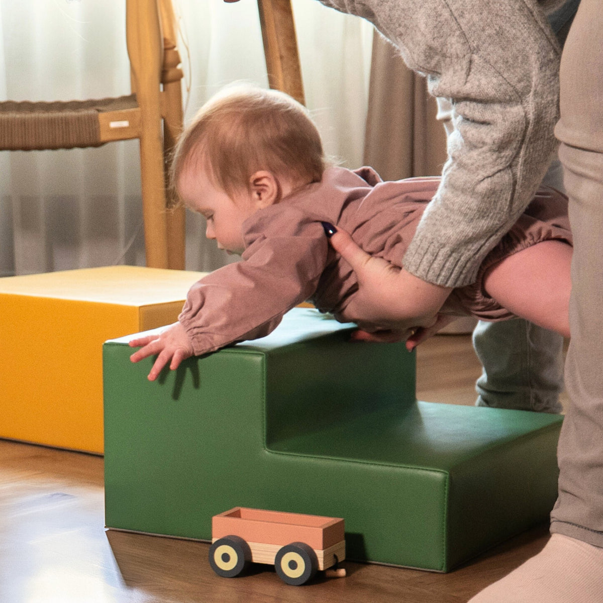 7. Baby supported by adult on green IGLU foam block with yellow block in background