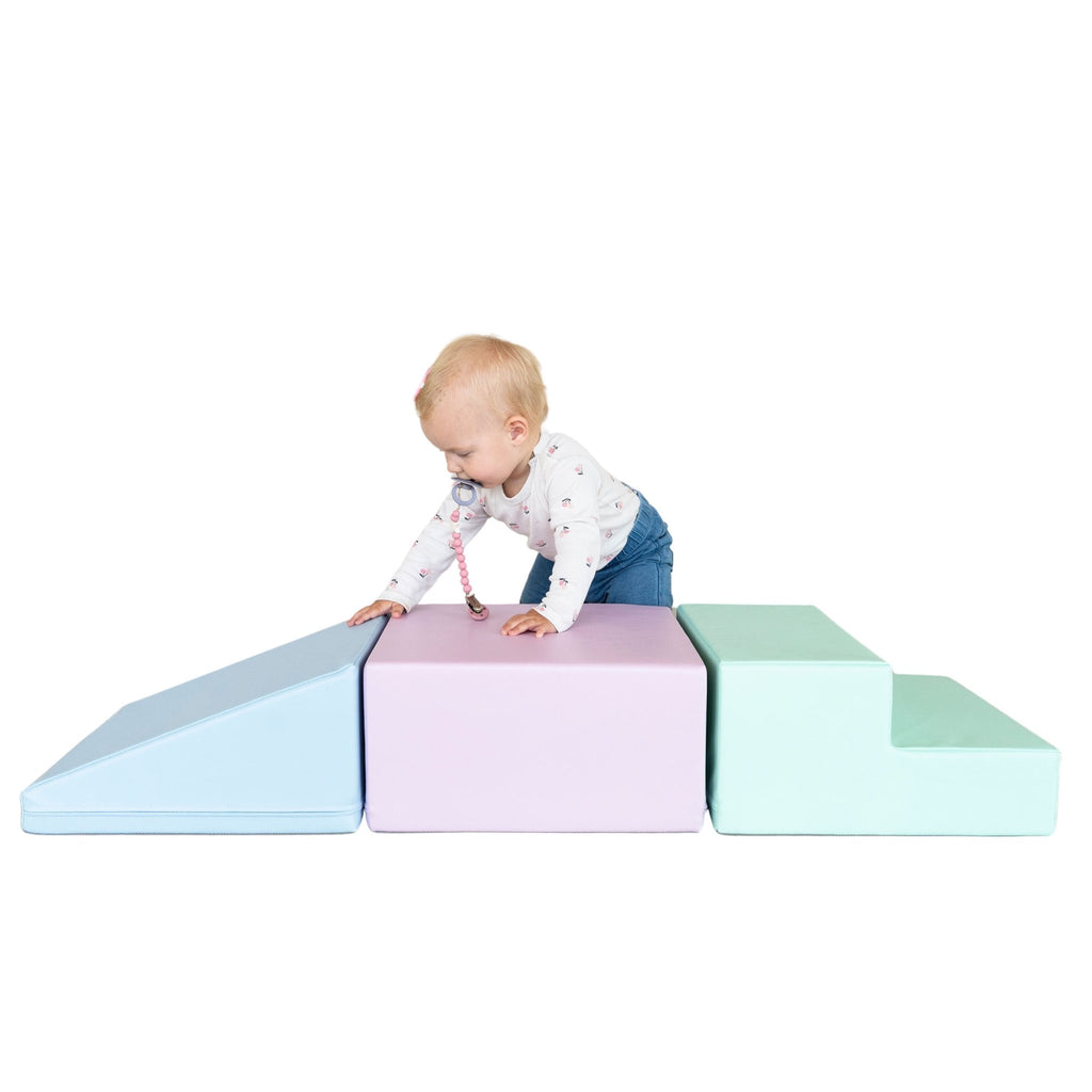 1. Toddler climbing on IGLU soft pastel foam blocks in a studio setting