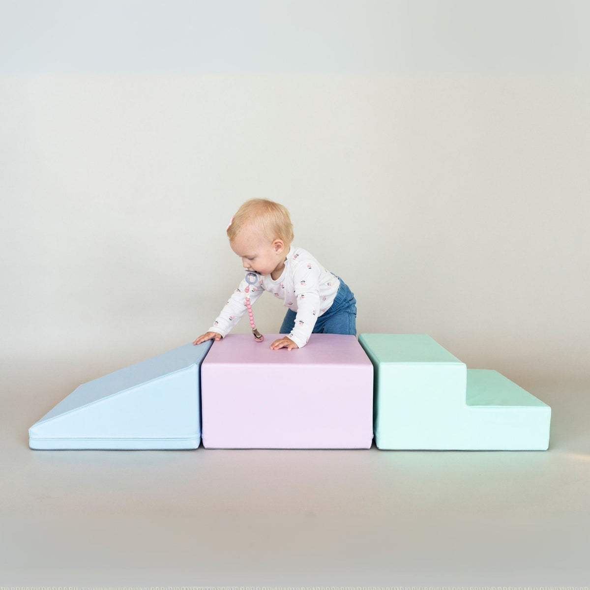 1. Toddler climbing on IGLU soft pastel foam blocks in a studio setting