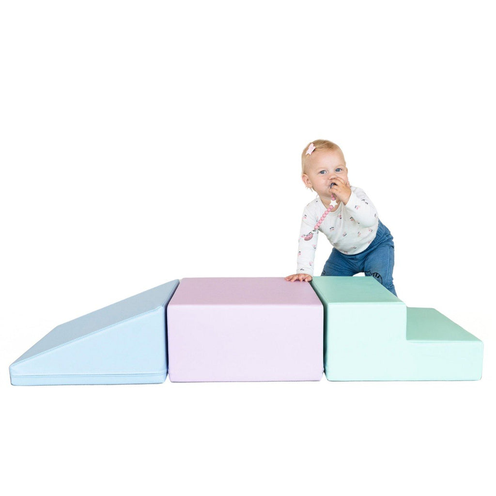 1. Toddler climbing on IGLU soft pastel foam blocks in a studio setting