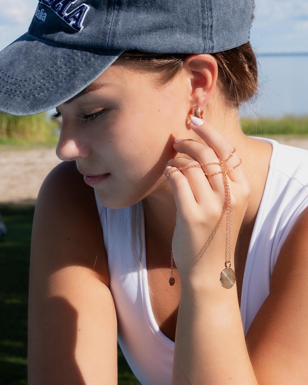 1. Woman wearing MyaMoon Illumi Infinity Pendant Necklace in rose gold, styled casually outdoors