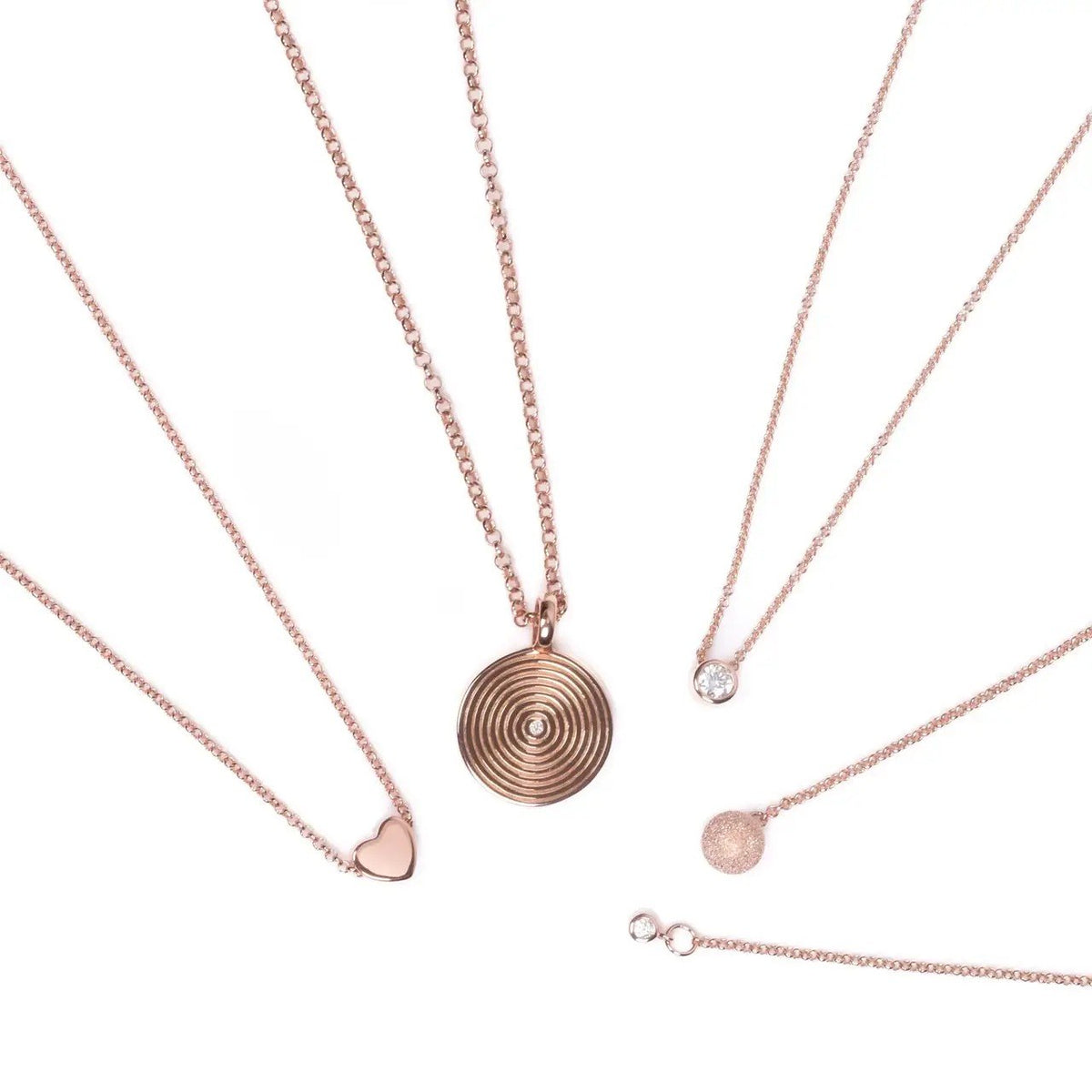 5. Flat lay of MyaMoon Illumi Infinity Pendant Necklace in rose gold with other jewelry pieces