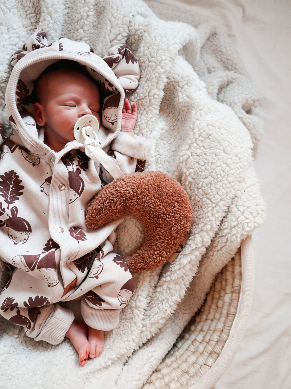 5. Sleeping baby in Zezuzulla eared jumpsuit with acorn print, cuddling a plush toy