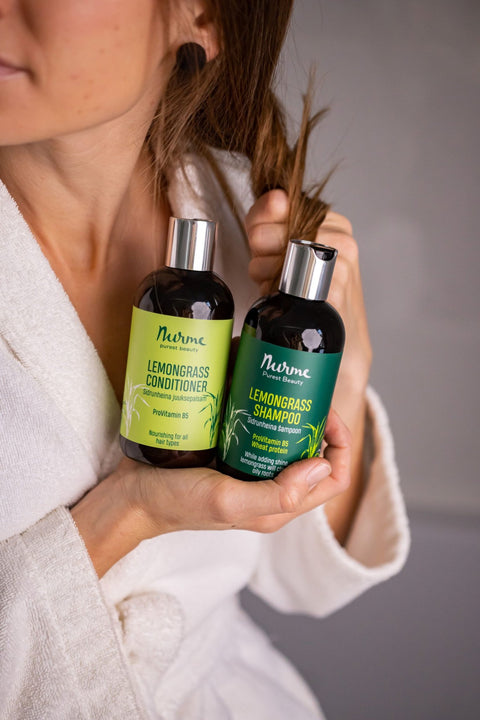 1. Woman in a white robe holding Nurme Lemongrass Shampoo and Conditioner set, highlighting natural hair care