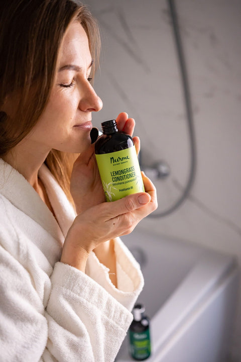 2. Woman in a white robe enjoying the scent of Nurme Lemongrass Conditioner, emphasizing natural ingredients