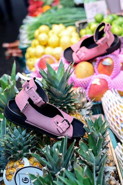 1. Women's pink TOKU Athens Vegan Sandals by Omaking displayed on pineapples at a market, showcasing eco-friendly design