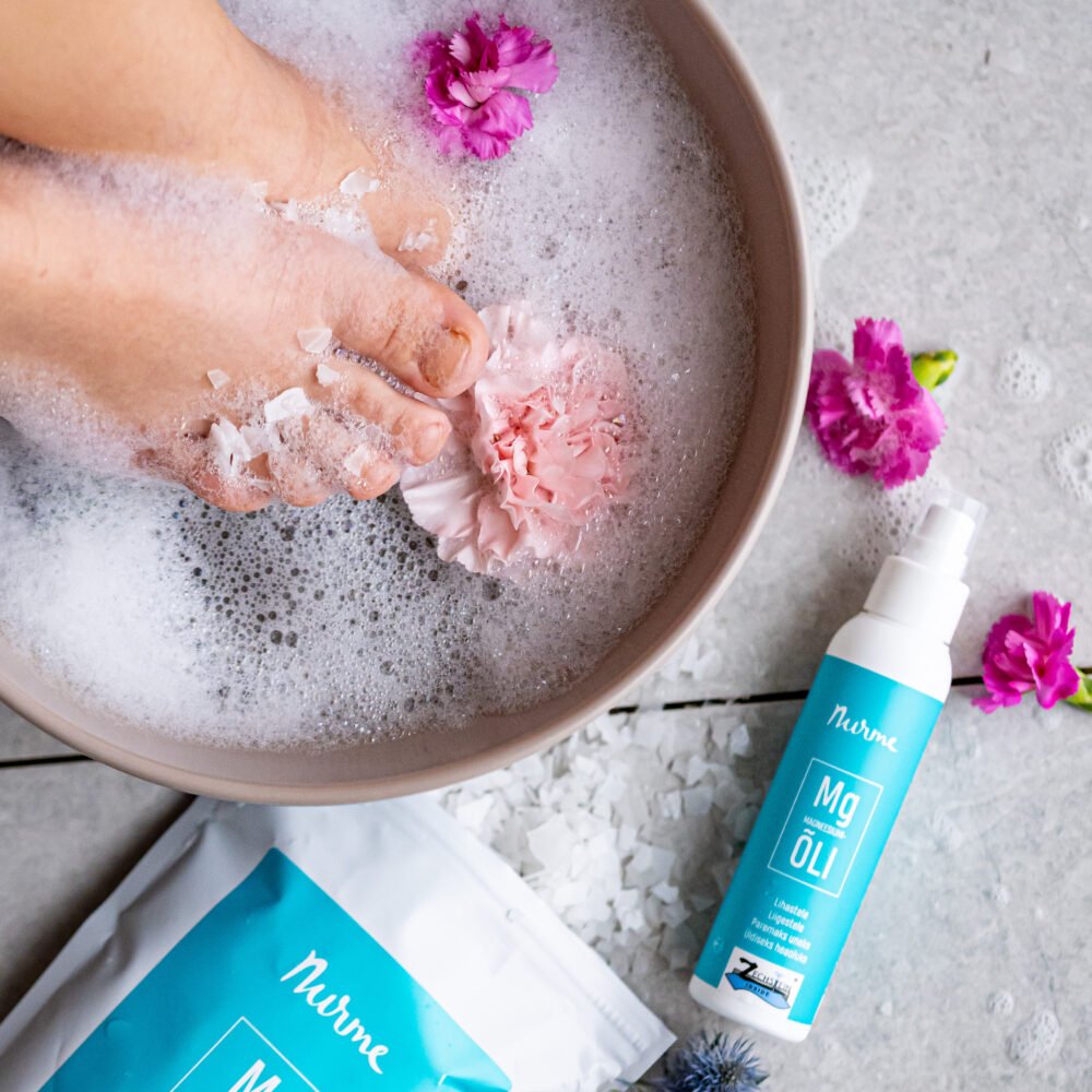 1. Nurme Magnesium Gift Set with oil and flakes in a relaxing foot bath setting with flowers