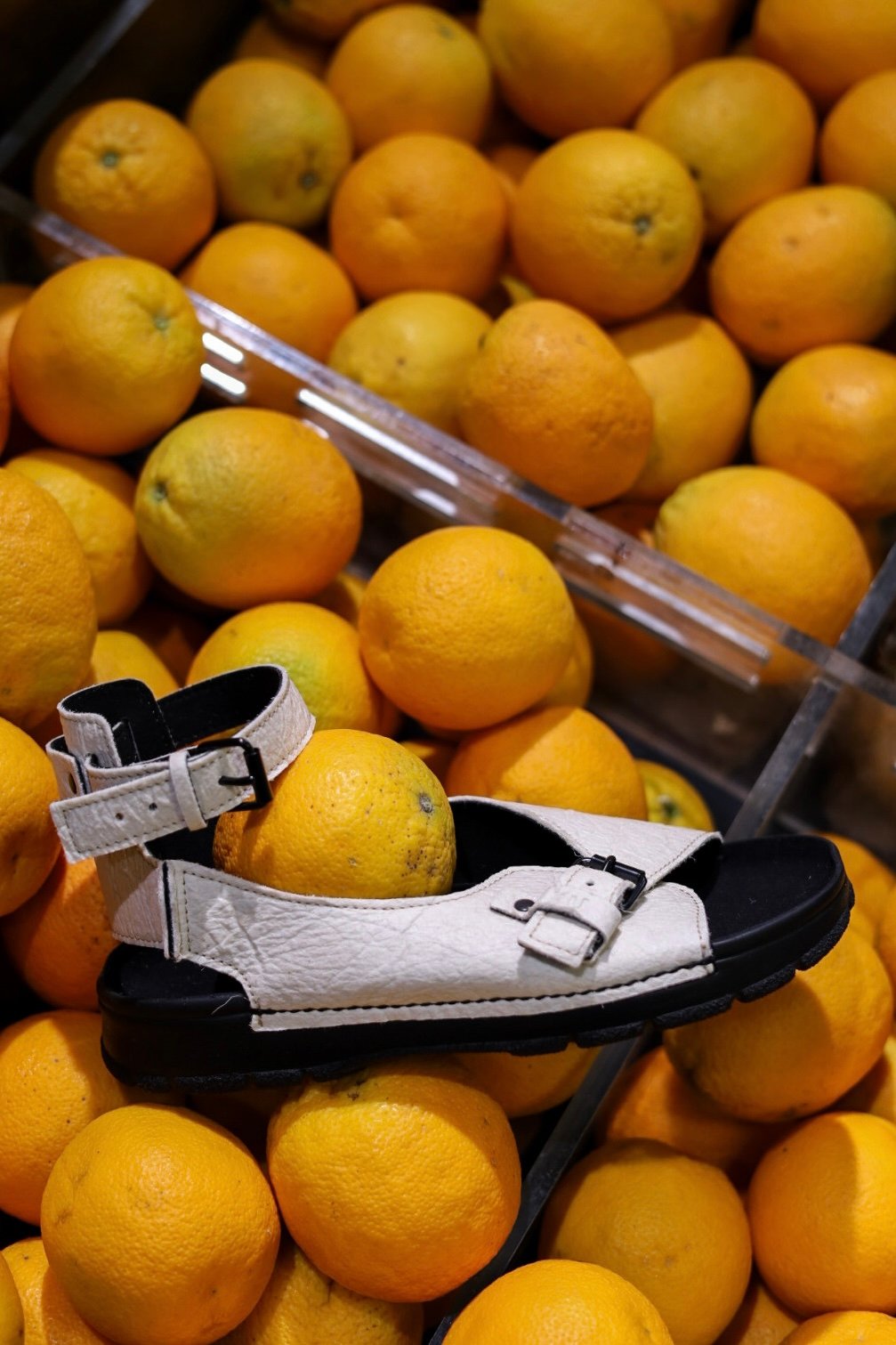 1. TOKU Athens Vegan Sandals in white piñatex leather displayed on oranges, highlighting sustainable design