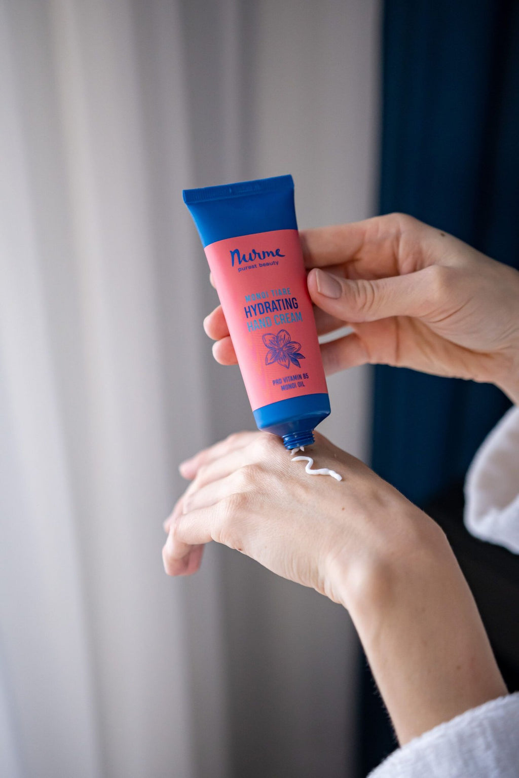 3. Woman applying Nurme hydrating hand cream with Monoi oil, shown in lifestyle setting