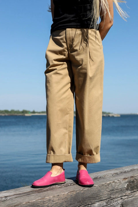 2. Women's pink TOKU London shoes by Omaking styled with beige pants, standing by the water