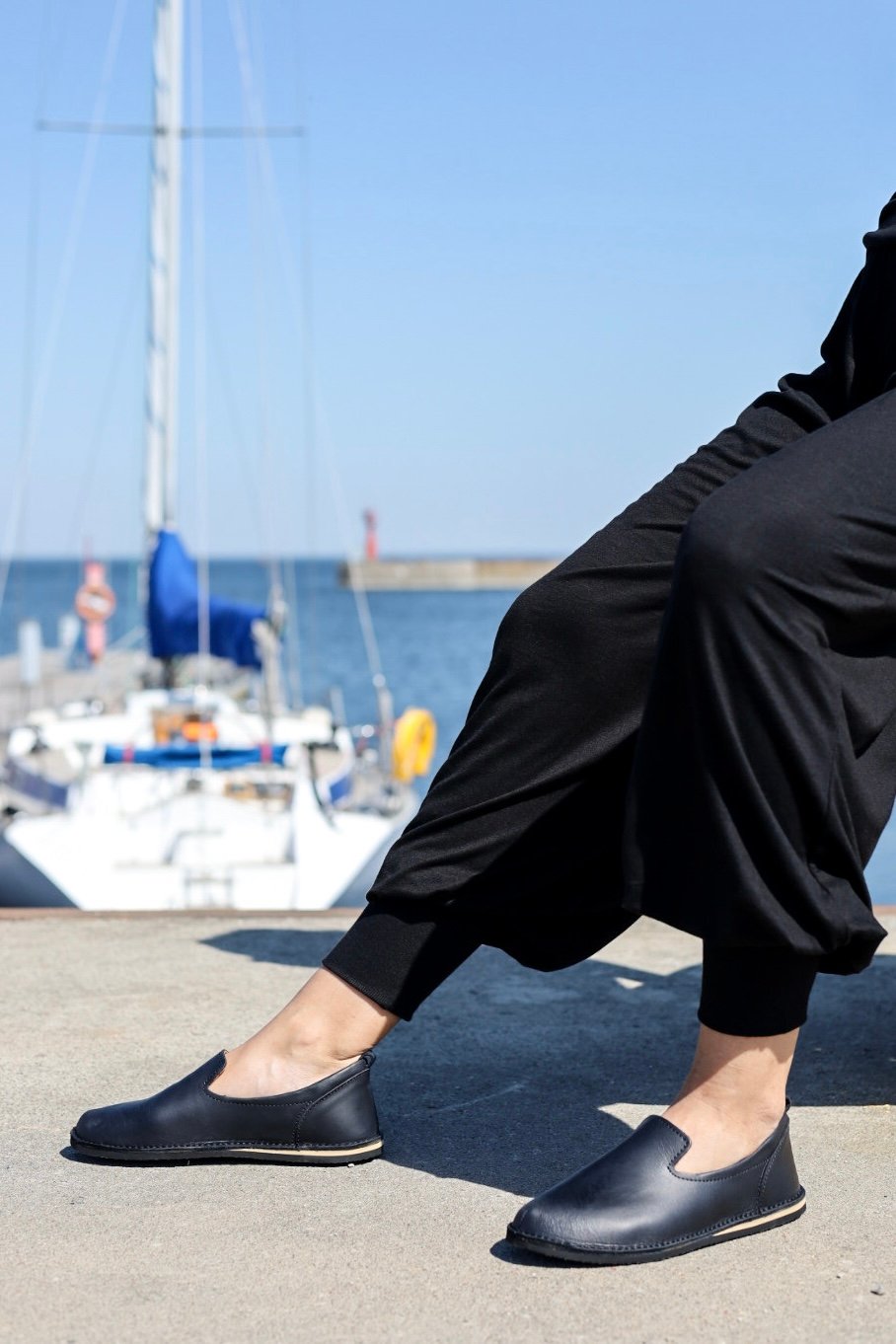 1. Women's black TOKU style London shoes by Omaking worn by model near a marina