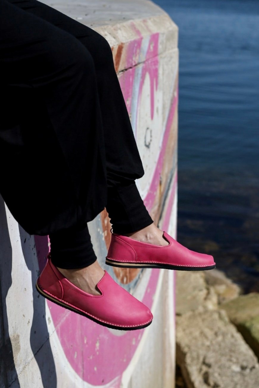 3. Women's pink TOKU London shoes by Omaking worn with black pants, sitting by graffiti wall