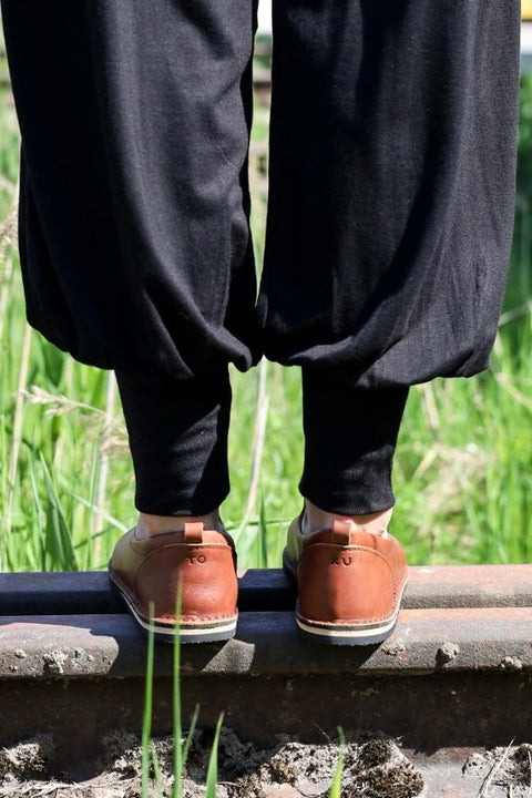 1. Lifestyle image of Omaking London classic brown shoes in TOKU style worn by a person standing on a railway track, shown from the back