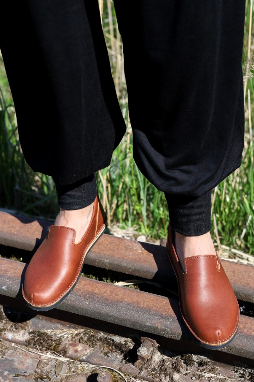 2. Lifestyle image of Omaking London classic brown shoes in TOKU style worn by a person standing on a railway track, shown from the front