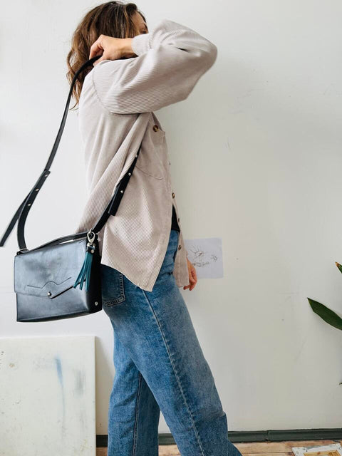 1. Woman wearing eleriinseim KOKUKA crossbody leather bag in black, styled with casual outfit