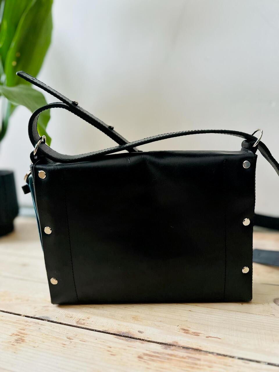 5. Back view of eleriinseim KOKUKA crossbody leather bag in black, showcasing rivet details