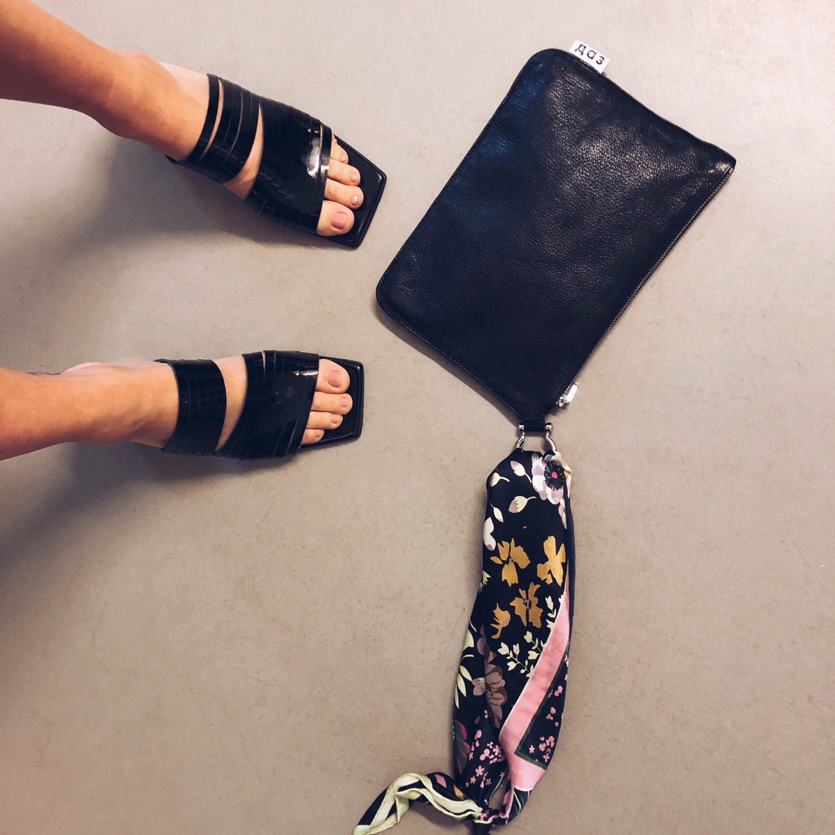 2. Women's black patent leather sandals styled with a floral scarf and clutch, shown from above