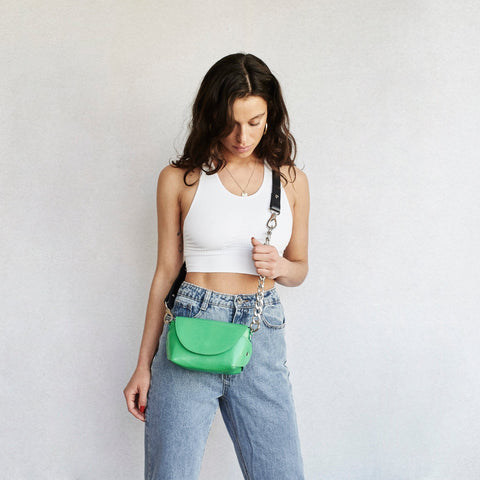 1. Woman wearing Daz Studio handmade neon green leather shoulder bag with adjustable strap, styled with casual outfit