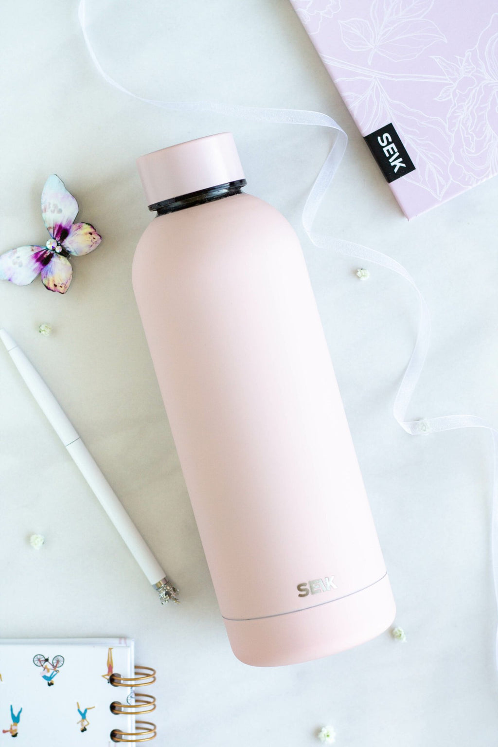 3. SEIK pink water bottle with cap shown on marble surface with butterfly decor