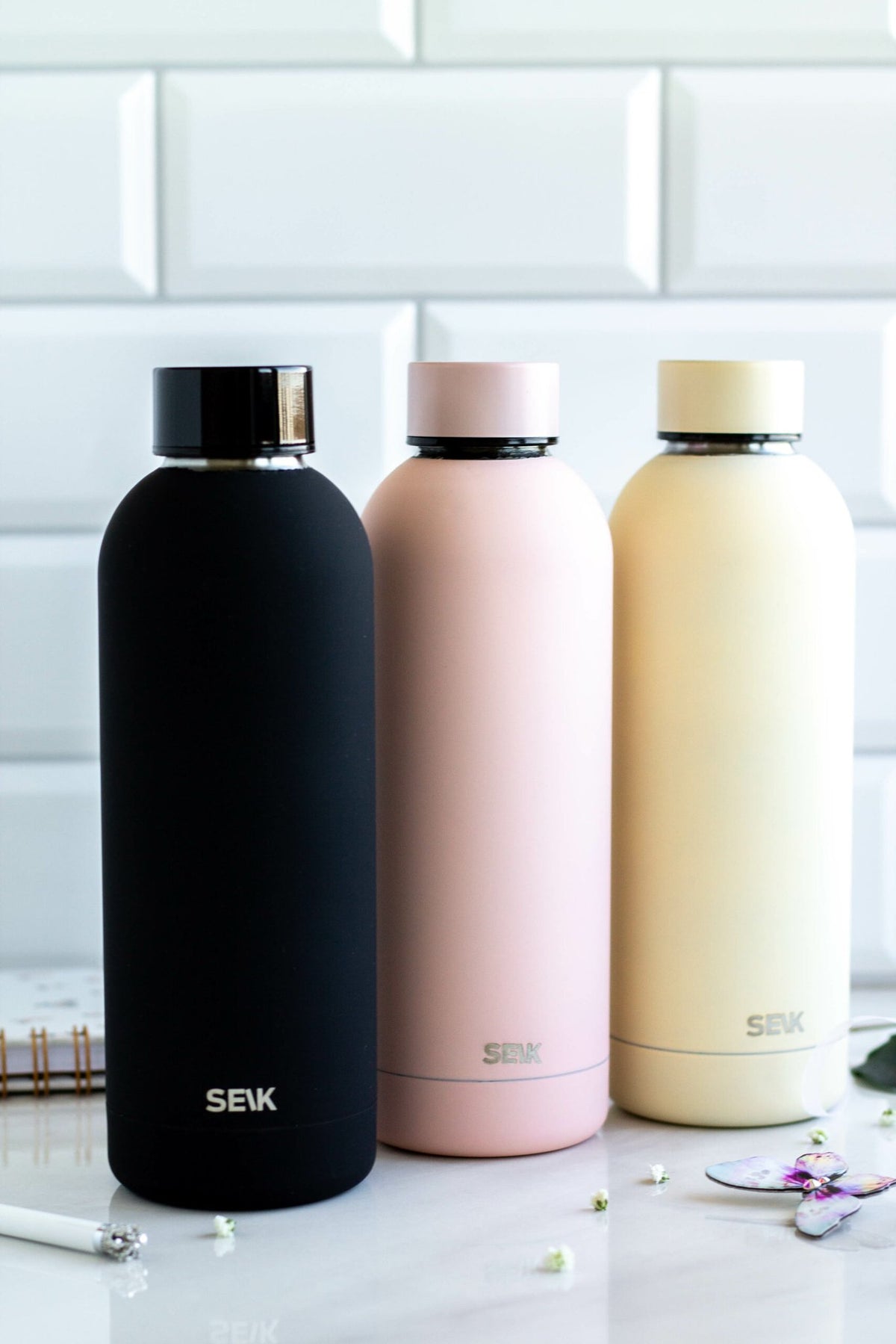 3. SEIK black, pink, and yellow water bottles with matte finish on a marble surface