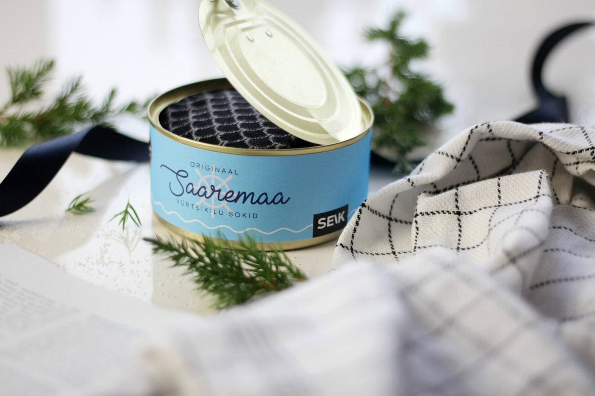 6. Open Saaremaa Vürtsikilu Socks tin with black patterned socks, styled with greenery and cloth