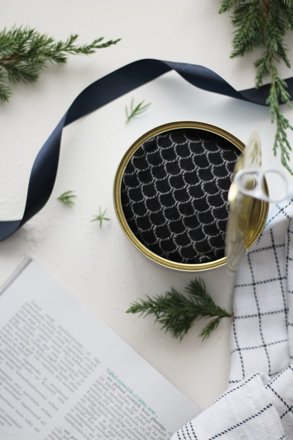 7. Top view of open Saaremaa Vürtsikilu Socks tin with black patterned socks, styled with ribbon
