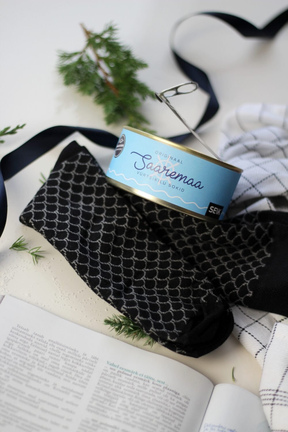 9. Saaremaa Vürtsikilu Socks with open tin, showing black pattern and SEIK branding, styled with book