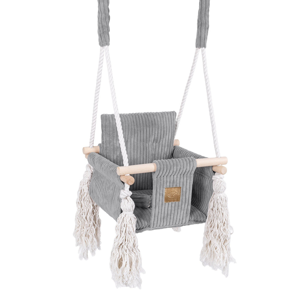 1. Grey corduroy indoor baby swing with wooden elements and decorative fringes, featuring sturdy cotton ropes and a cushioned seat, ideal for modern living spaces