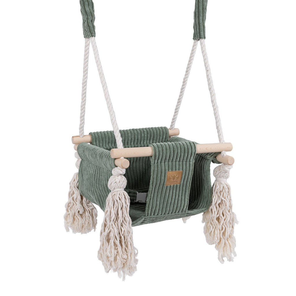 1. Olive green indoor baby swing with corduroy seat, wooden elements, and decorative fringes, designed for infants, shown hanging with white cotton ropes