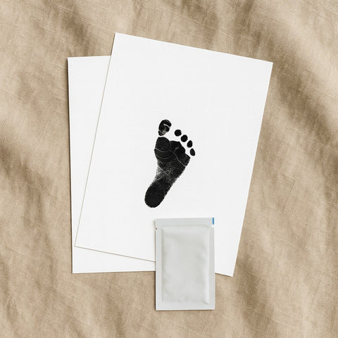 3. Close-up of Beebila ink-free print kit with footprint on white paper and included wipe, on beige fabric