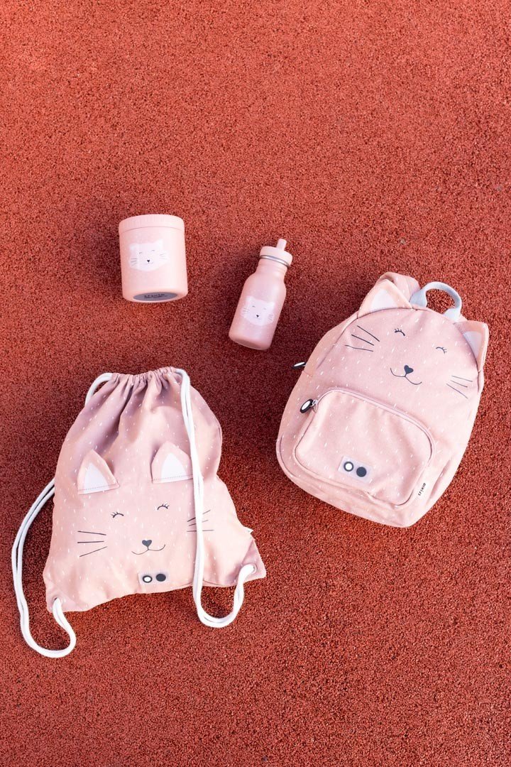 6. Flat lay of Trixie Baby Mrs. Cat lunch pot, bottle, and backpacks on red surface