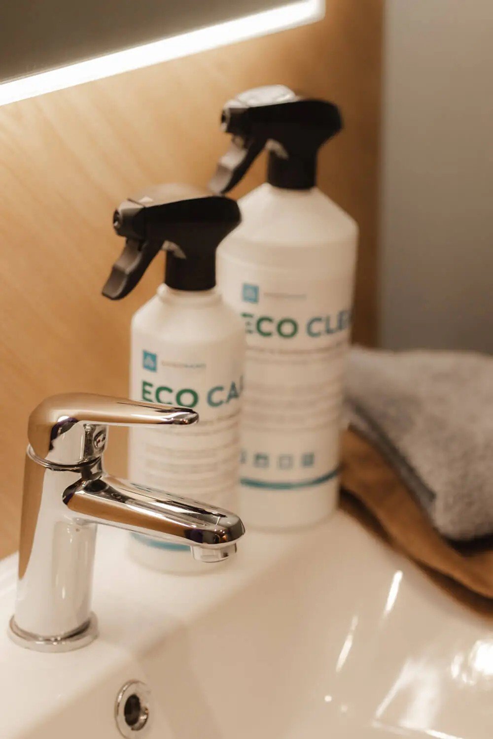 1. GoGoNano EcoCare and EcoClean bottles on bathroom sink with modern faucet, highlighting eco-friendly cleaning solutions