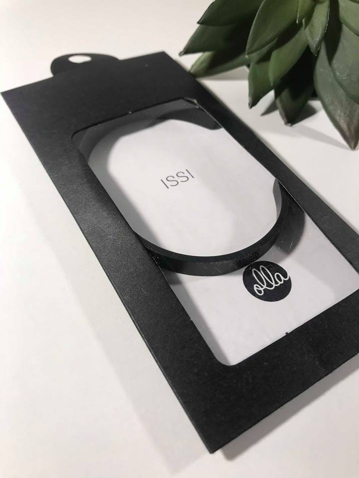 1. Black Olla men's bracelet in packaging with ISSI engraving, displayed on white surface with green plant accent