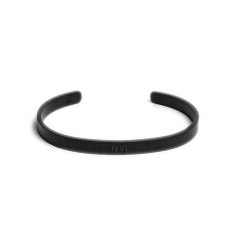 2. Matte black Olla men's bracelet with ISSI engraving, shown on white background highlighting open cuff design