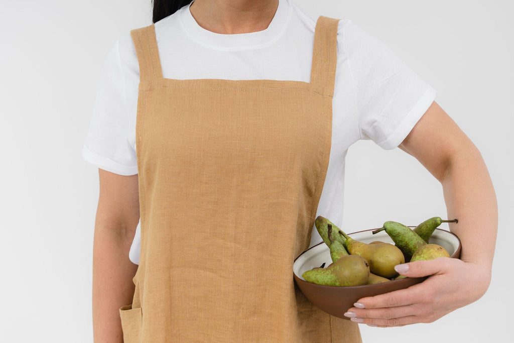 7. Woman in beige Japanese-style linen apron holding bowl of pears, shown from waist up