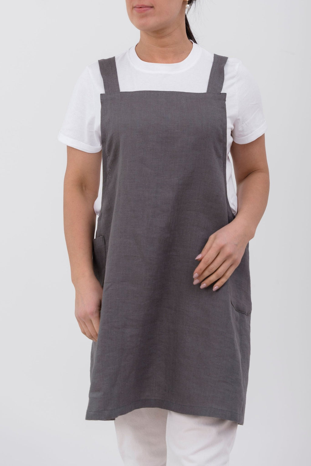 14. Front view of woman wearing grey Japanese-style linen apron with pockets over white shirt